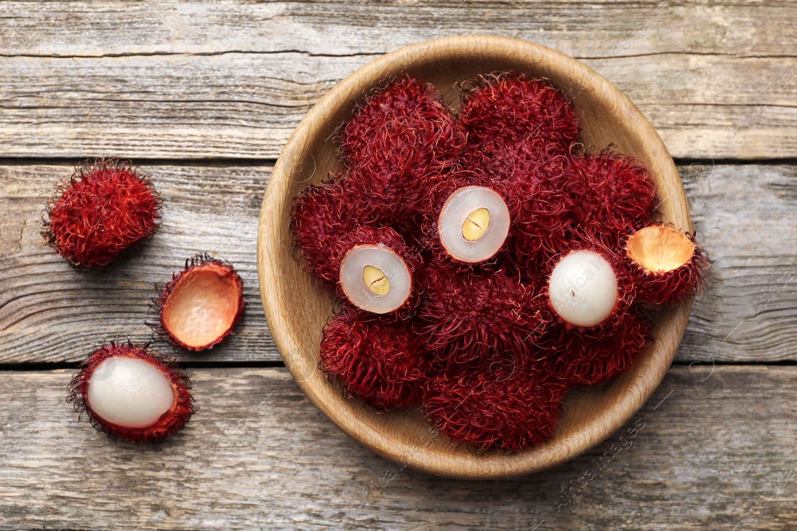 Photo of Delicious ripe rambutans on wooden table, top view