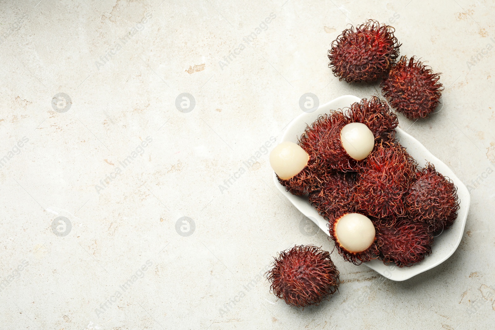 Photo of Delicious ripe rambutans on light grey table, top view. Space for text