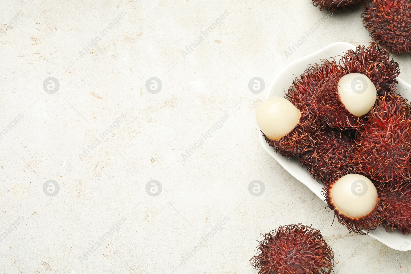 Photo of Delicious ripe rambutans on light grey table, top view. Space for text