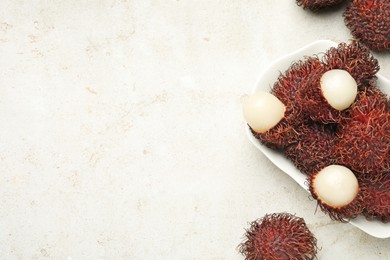 Photo of Delicious ripe rambutans on light grey table, top view. Space for text