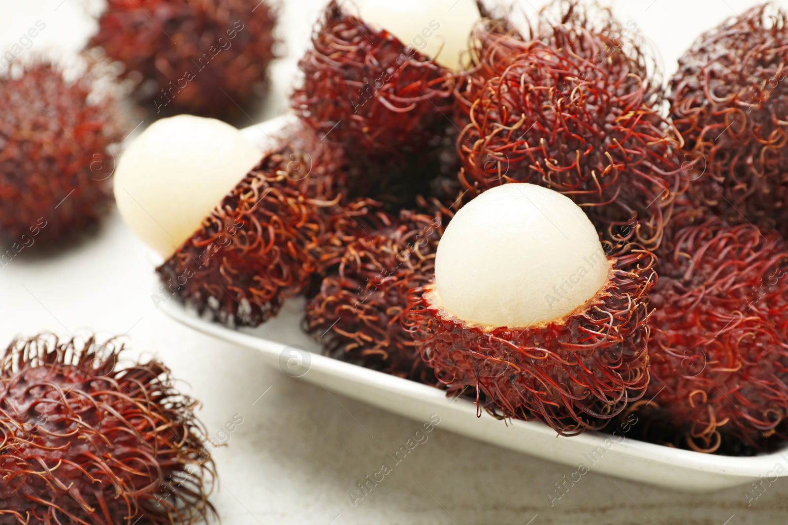 Photo of Delicious ripe rambutans on light grey table, closeup