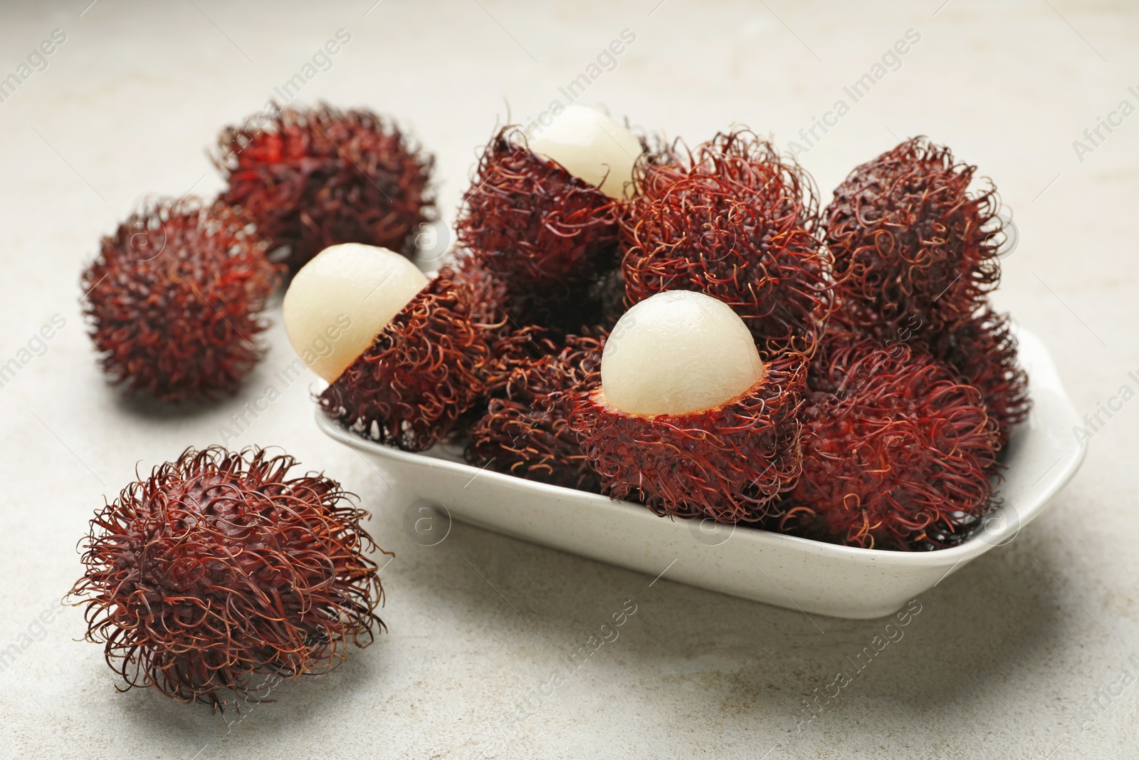 Photo of Delicious ripe rambutans on light grey table, closeup