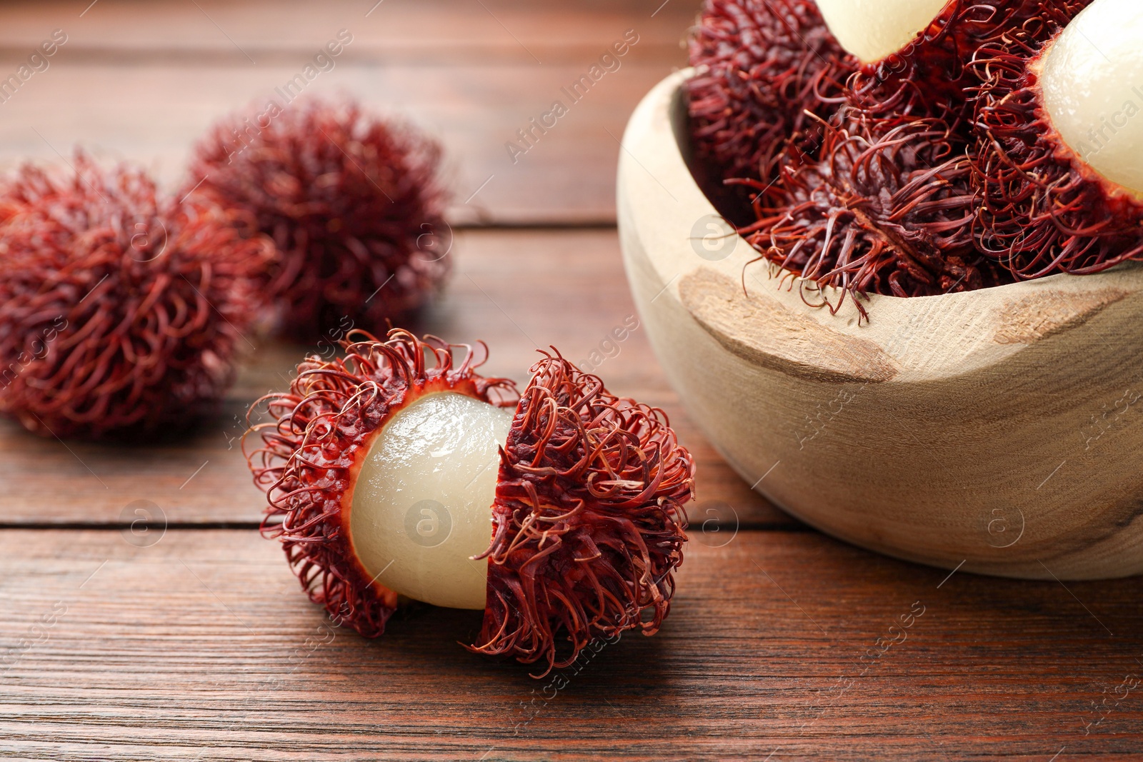 Photo of Delicious ripe rambutans on wooden table, closeup