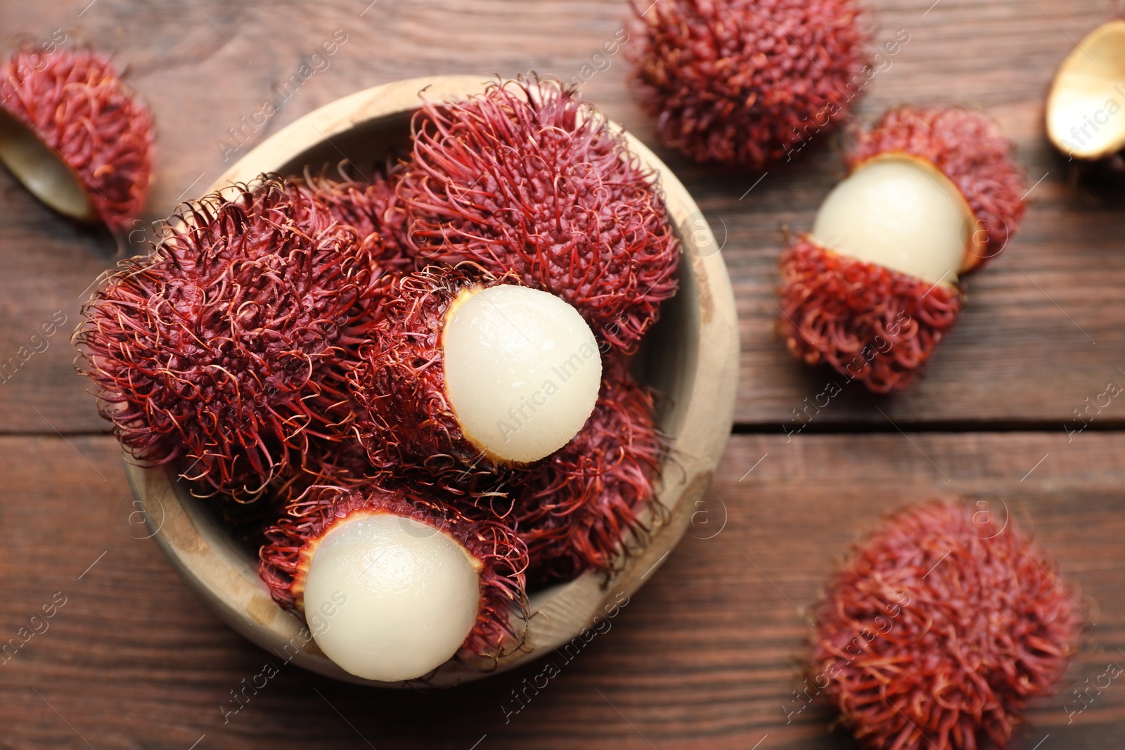 Photo of Delicious ripe rambutans in bowl on wooden table, top view