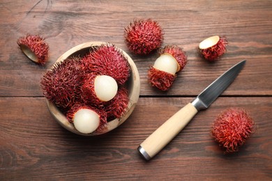 Photo of Delicious ripe rambutans in bowl and knife on wooden table, flat lay