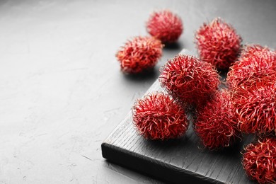 Photo of Delicious ripe rambutans on black table, closeup. Space for text