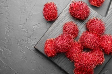 Photo of Delicious ripe rambutans on black table, top view. Space for text