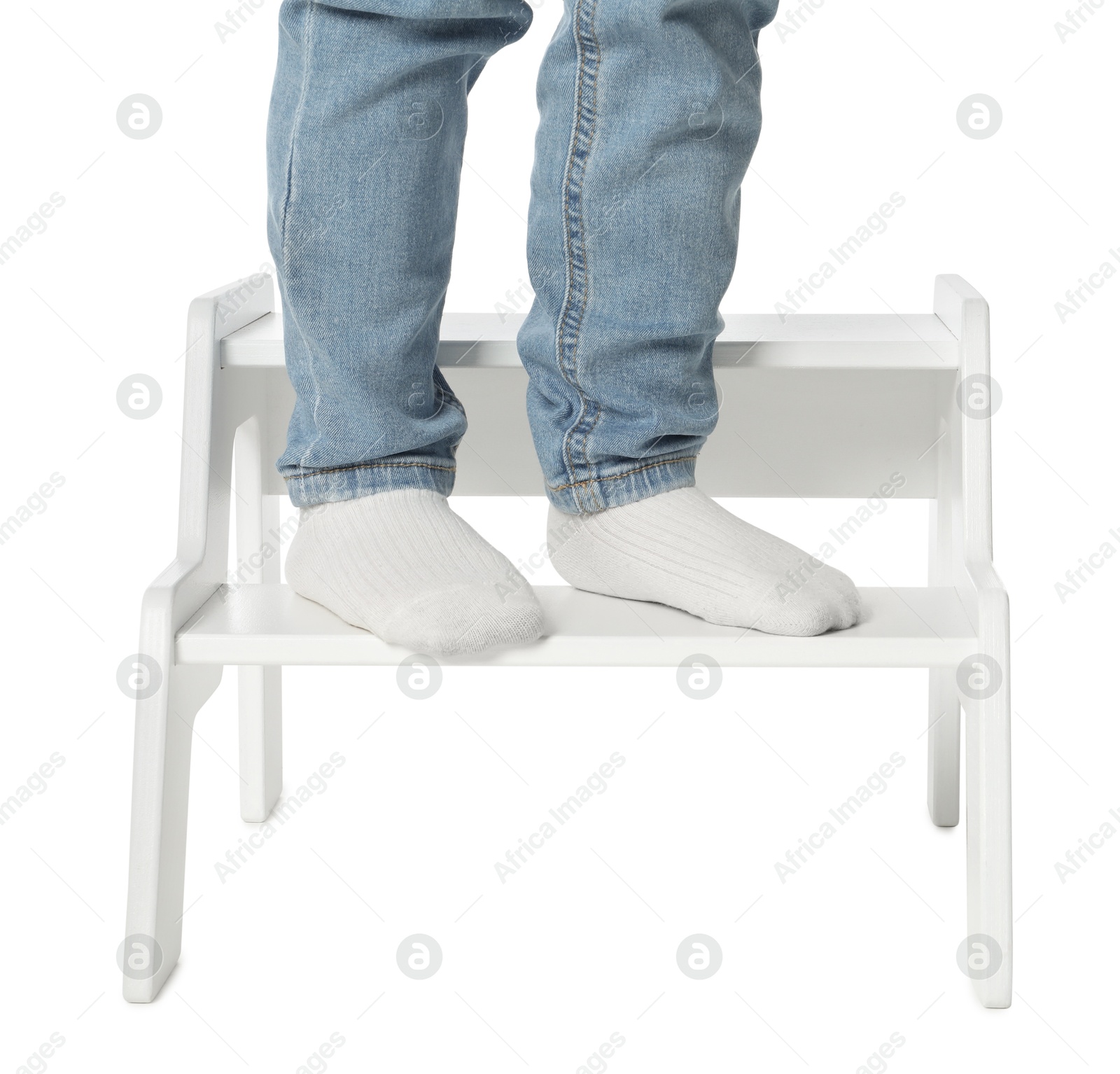 Photo of Little boy standing on step stool against white background, closeup