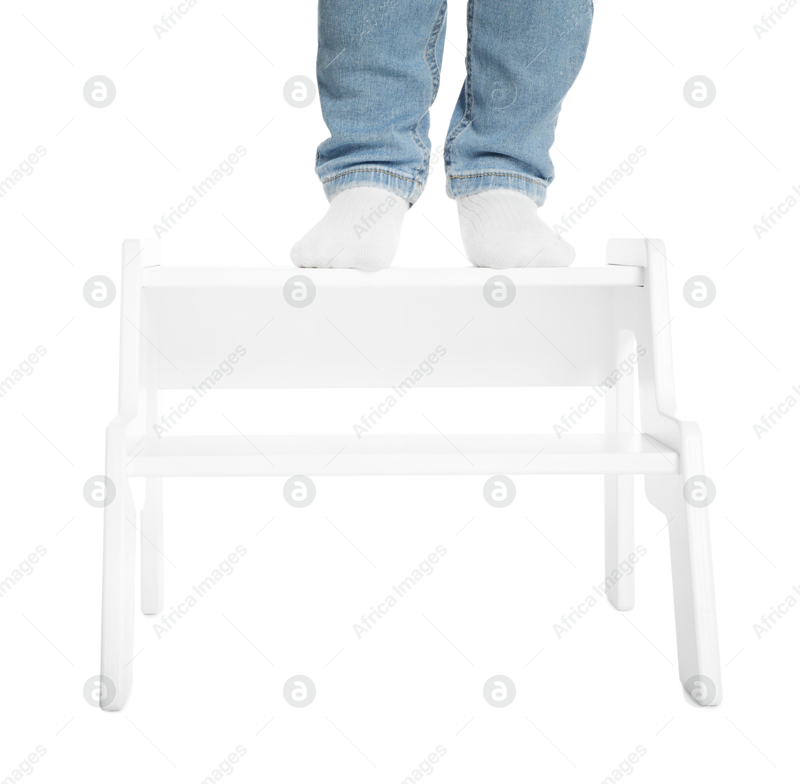 Photo of Little boy standing on step stool against white background, closeup