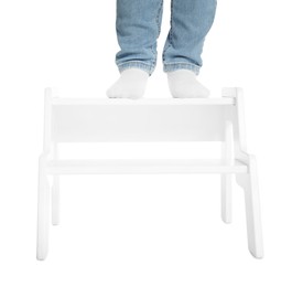 Photo of Little boy standing on step stool against white background, closeup