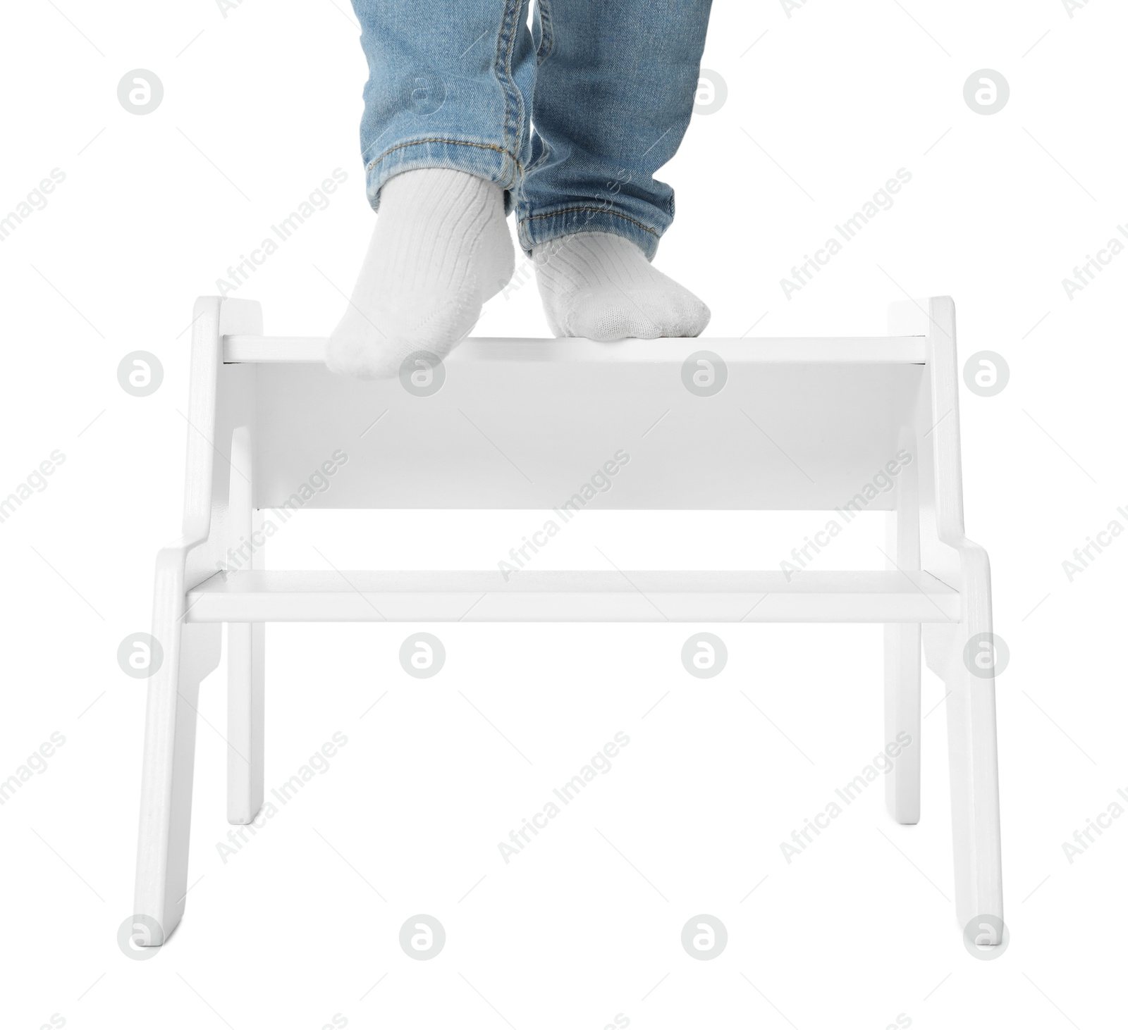 Photo of Little boy standing on step stool against white background, closeup