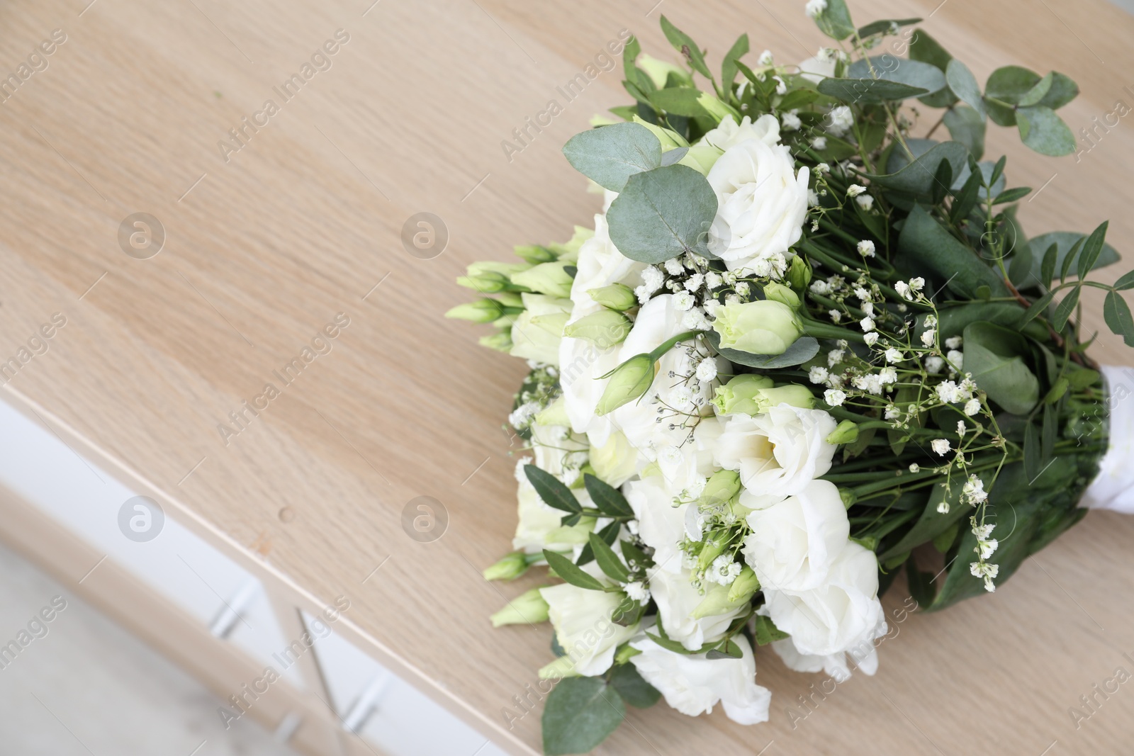 Photo of Beautiful wedding bouquet on wooden nightstand, above view. Space for text