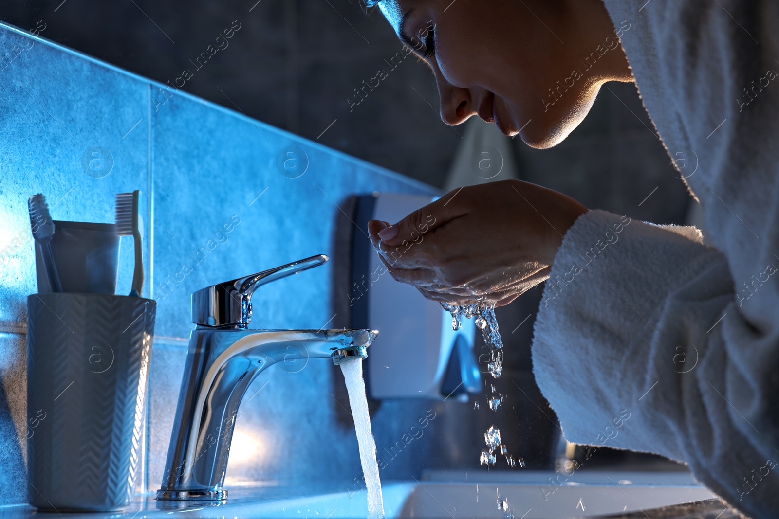 Photo of Woman washing her face over sink in bathroom