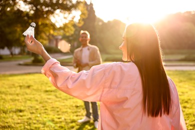 Photo of Young woman and man playing badminton in park on sunny day, selective focus