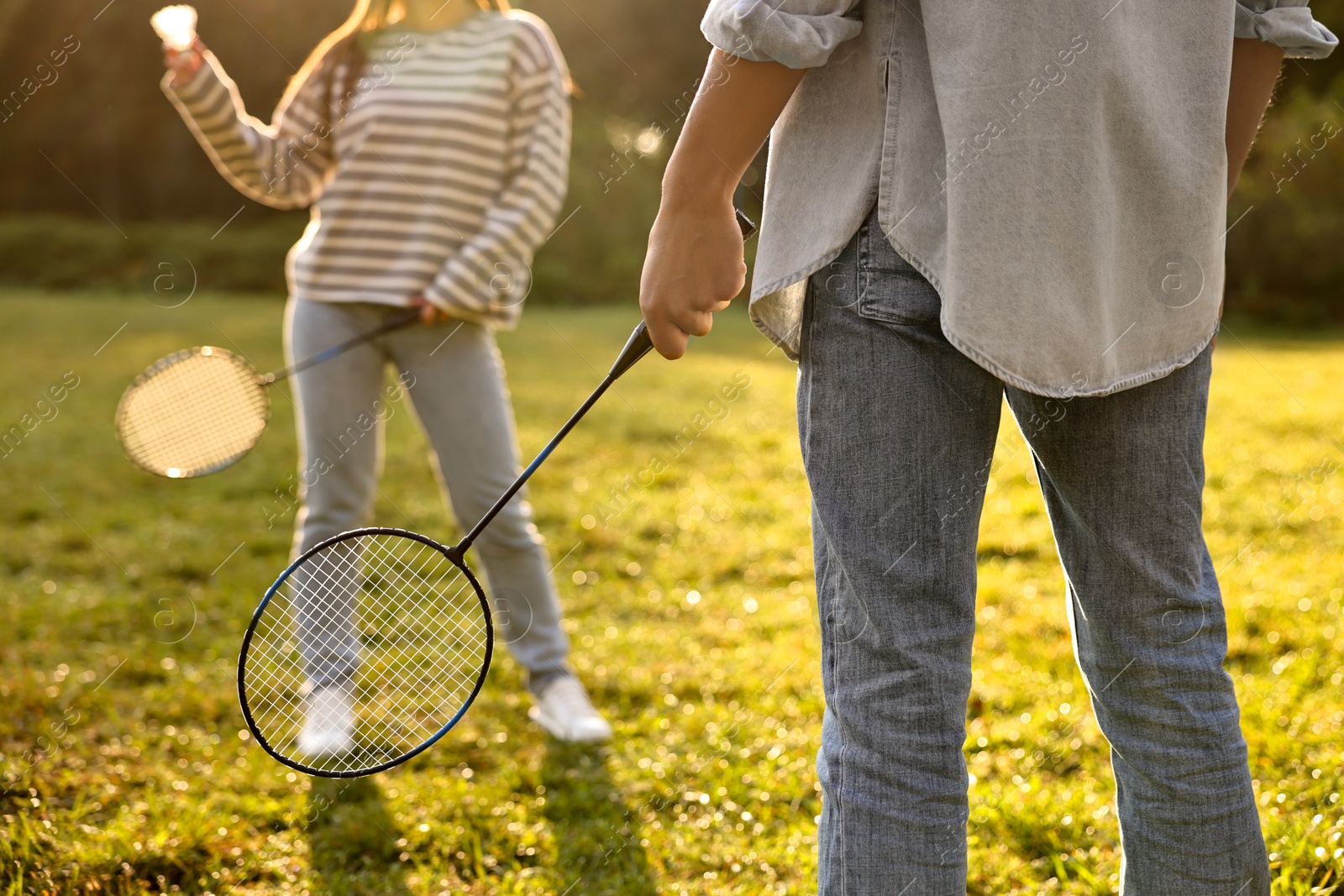 Photo of Woman and man playing badminton in park on sunny day, closeup