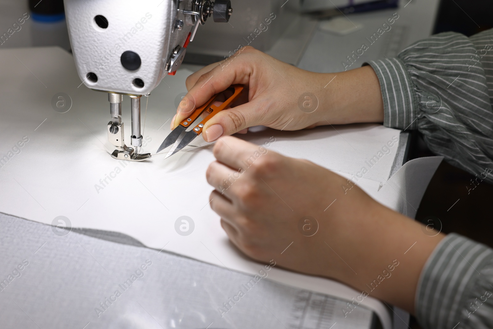 Photo of Woman working with sewing machine in professional workshop, closeup