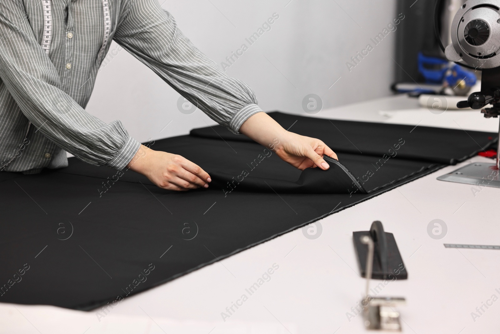 Photo of Young woman working at white table in professional workshop, closeup