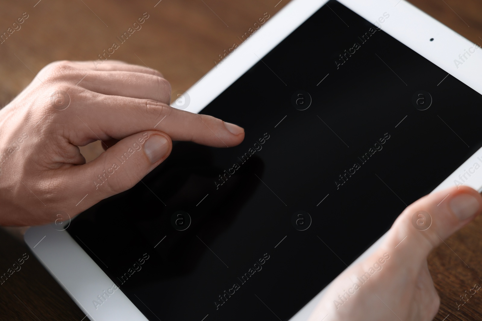 Photo of Businessman using tablet at wooden table, closeup. Modern technology