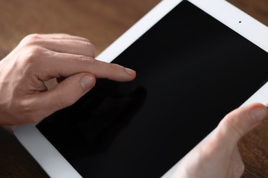 Businessman using tablet at wooden table, closeup. Modern technology