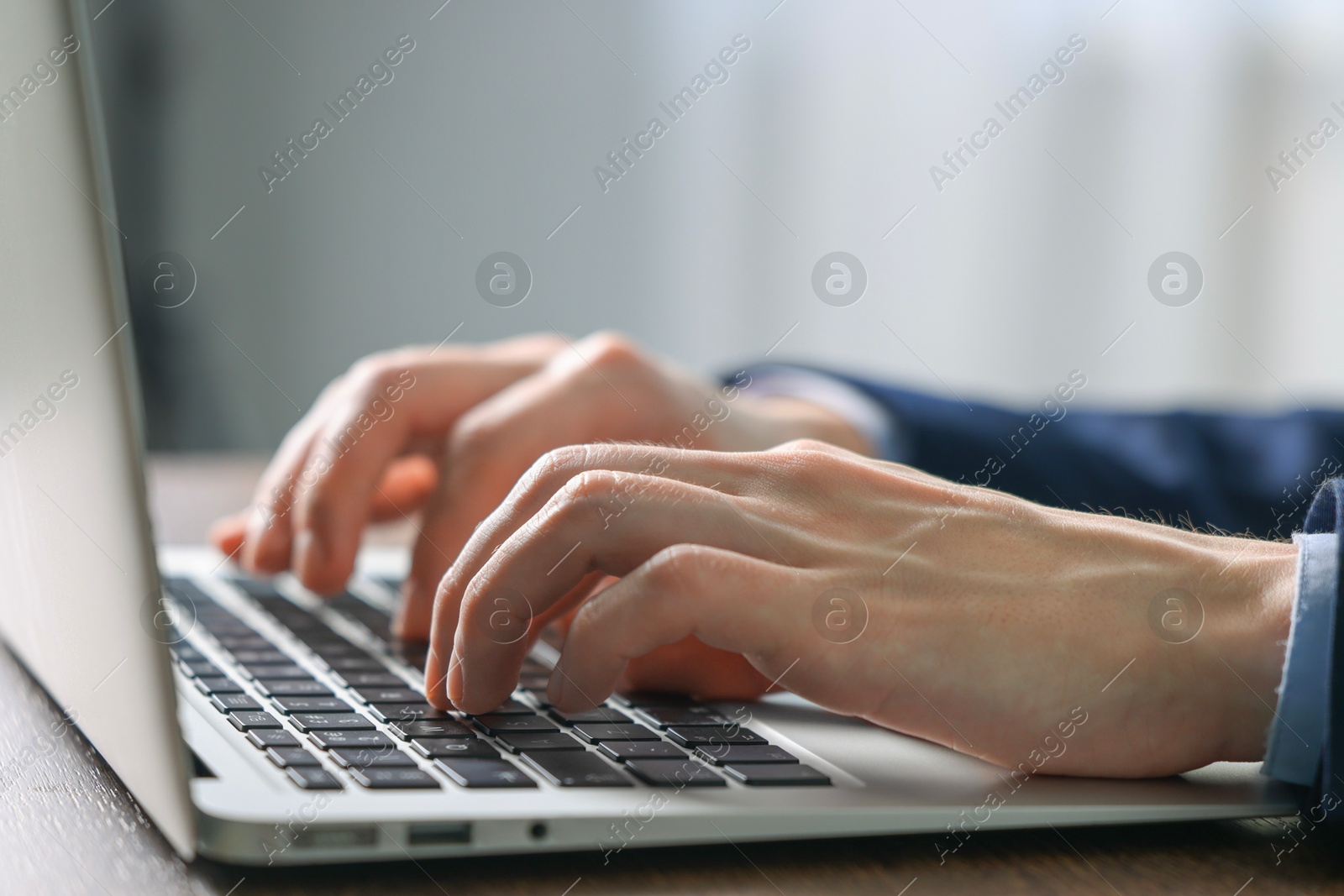 Photo of Businessman using laptop indoors, closeup. Modern technology