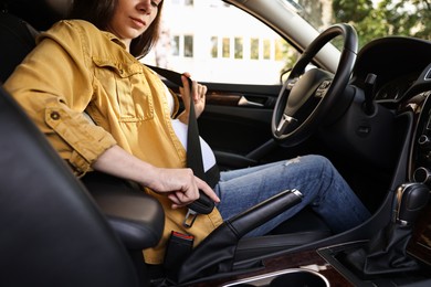 Photo of Pregnant woman fastening safety belt in car, closeup