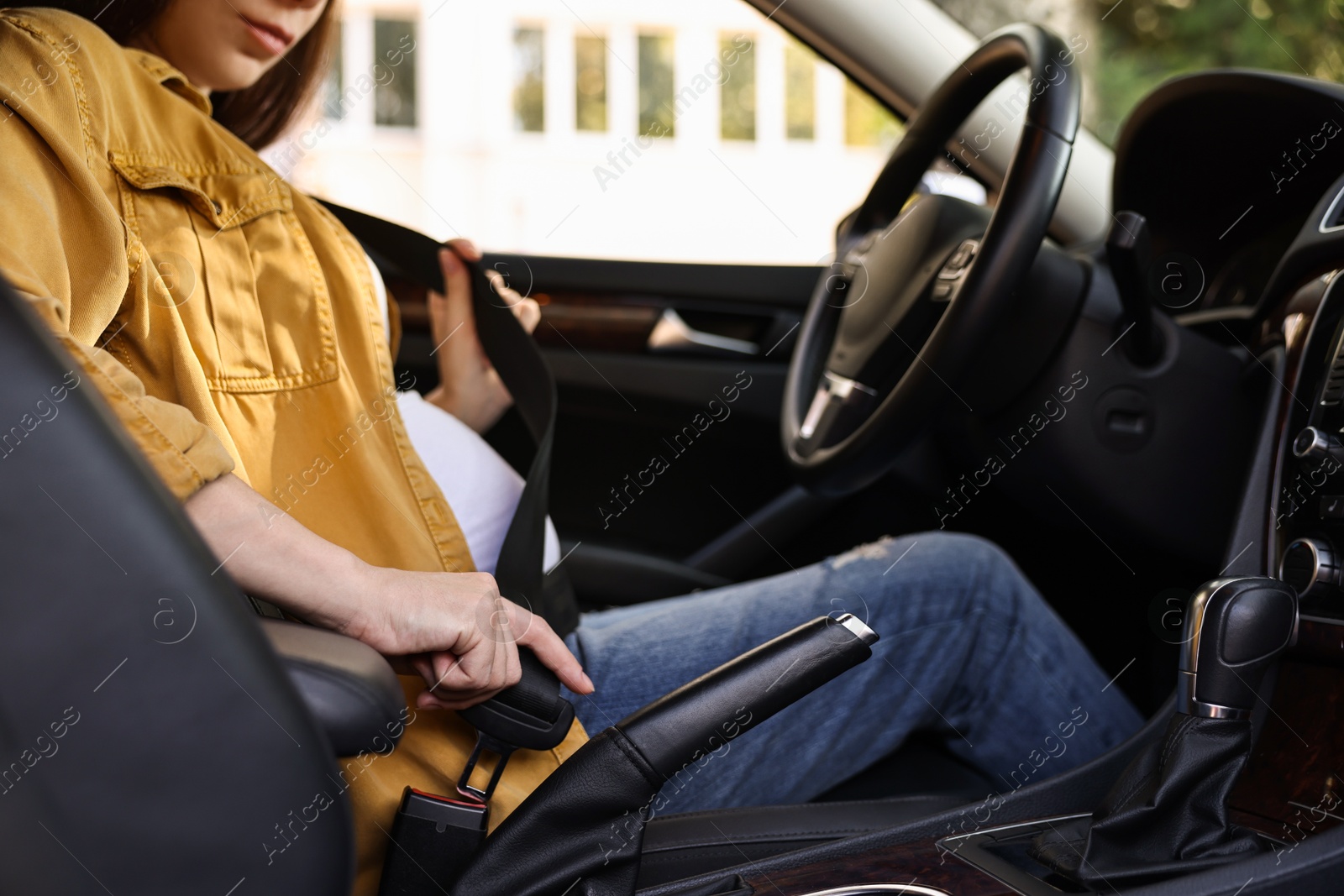 Photo of Pregnant woman fastening safety belt in car, closeup