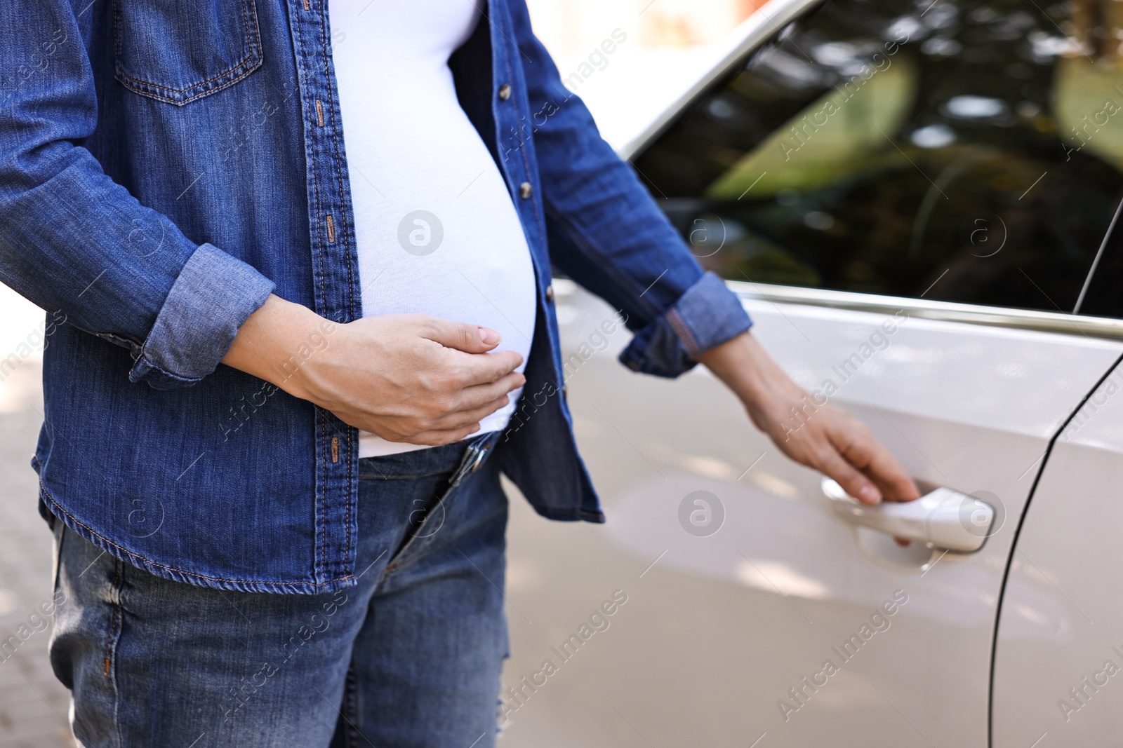 Photo of Pregnant woman opening car door outdoors, closeup