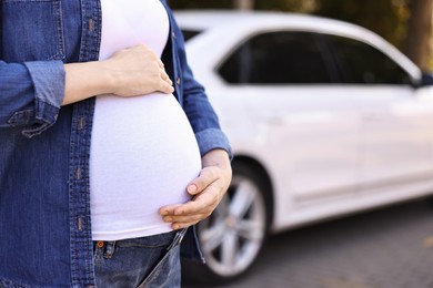 Photo of Pregnant woman near car outdoors, closeup. Space for text