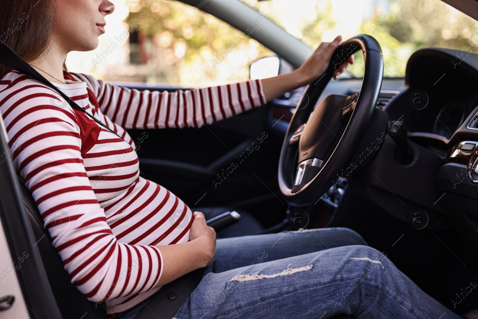 Photo of Pregnant woman with safety belt driving car, closeup