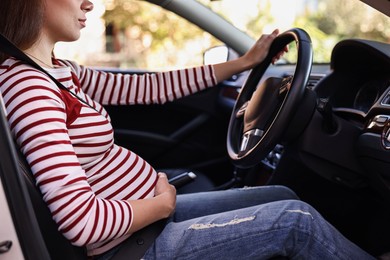 Photo of Pregnant woman with safety belt driving car, closeup