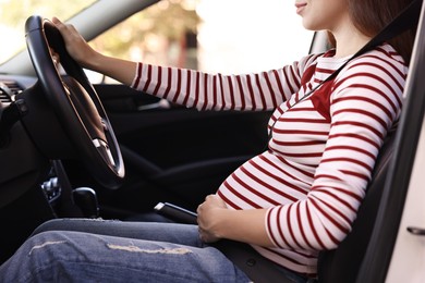 Photo of Pregnant woman with safety belt driving car, closeup