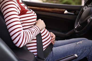 Photo of Pregnant woman with safety belt in car, closeup