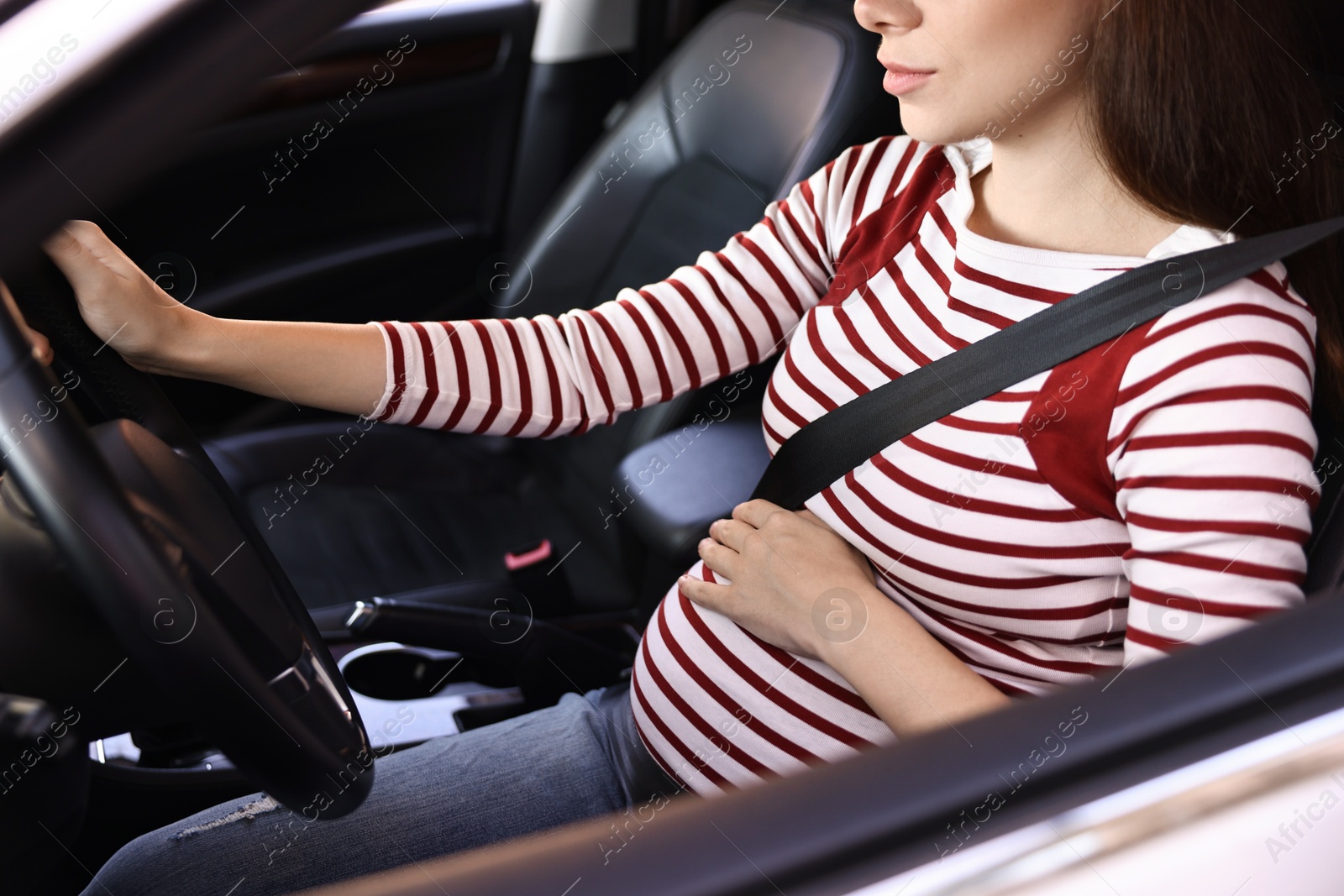 Photo of Pregnant woman with safety belt driving car, closeup