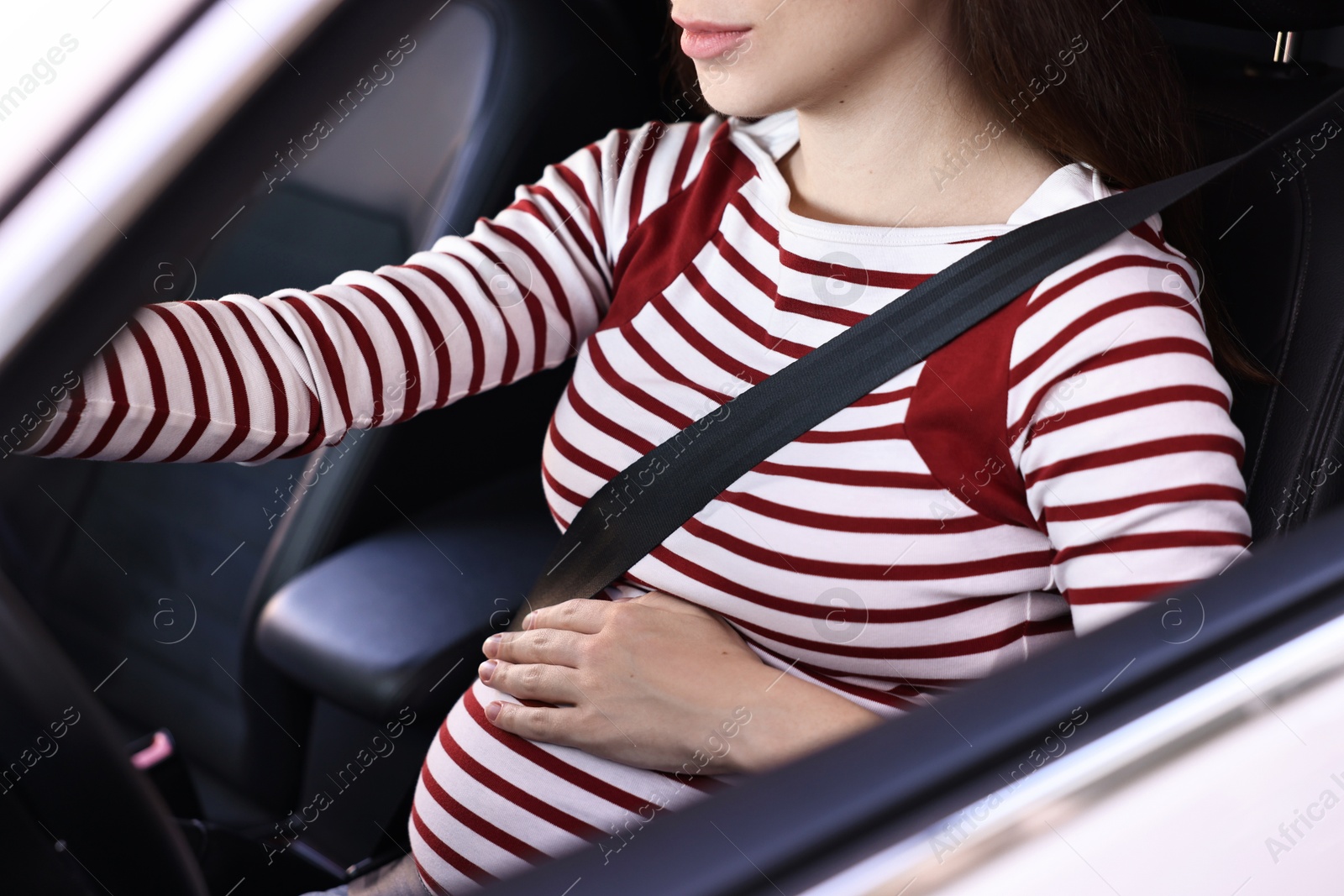 Photo of Pregnant woman with safety belt driving car, closeup