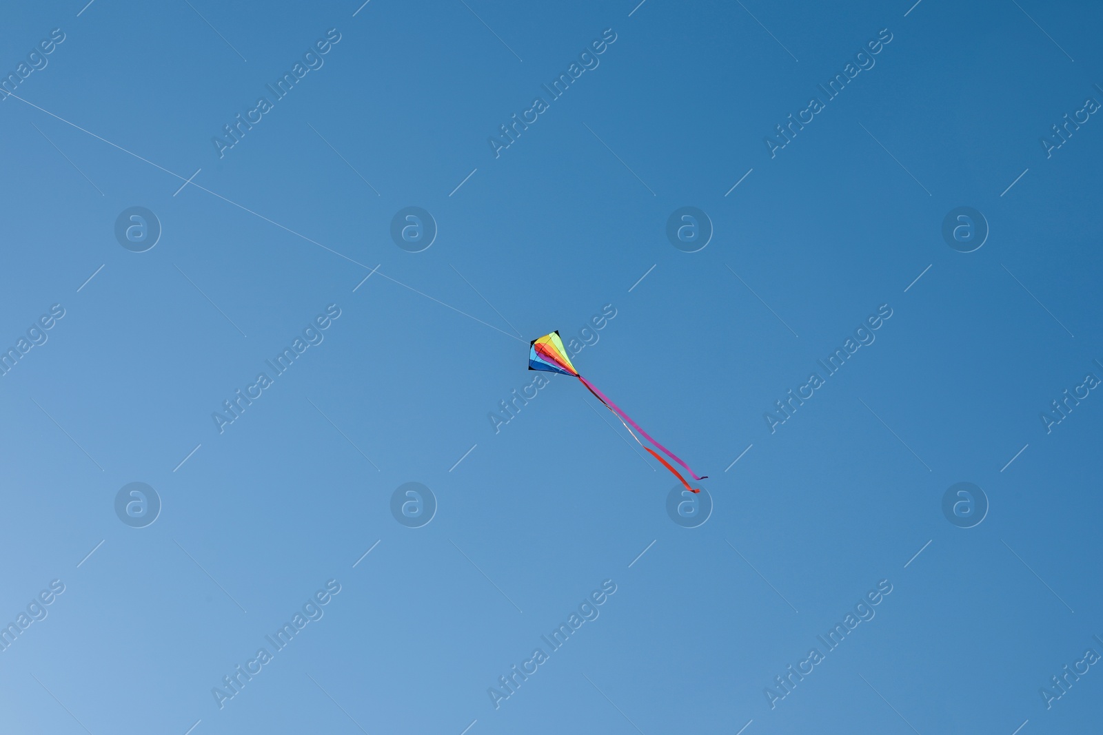 One colorful kite flying in blue sky Photo of One colorful kite flying in blue sky