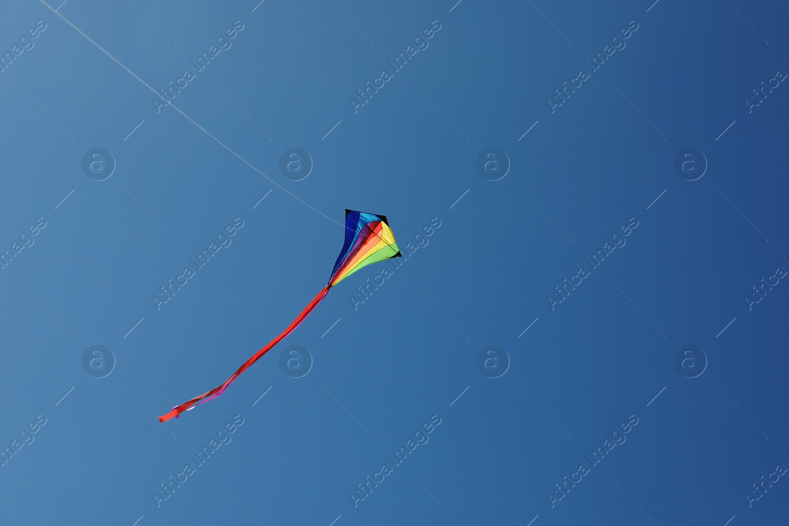One colorful kite flying in blue sky. Space for text Photo of One colorful kite flying in blue sky. Space for text