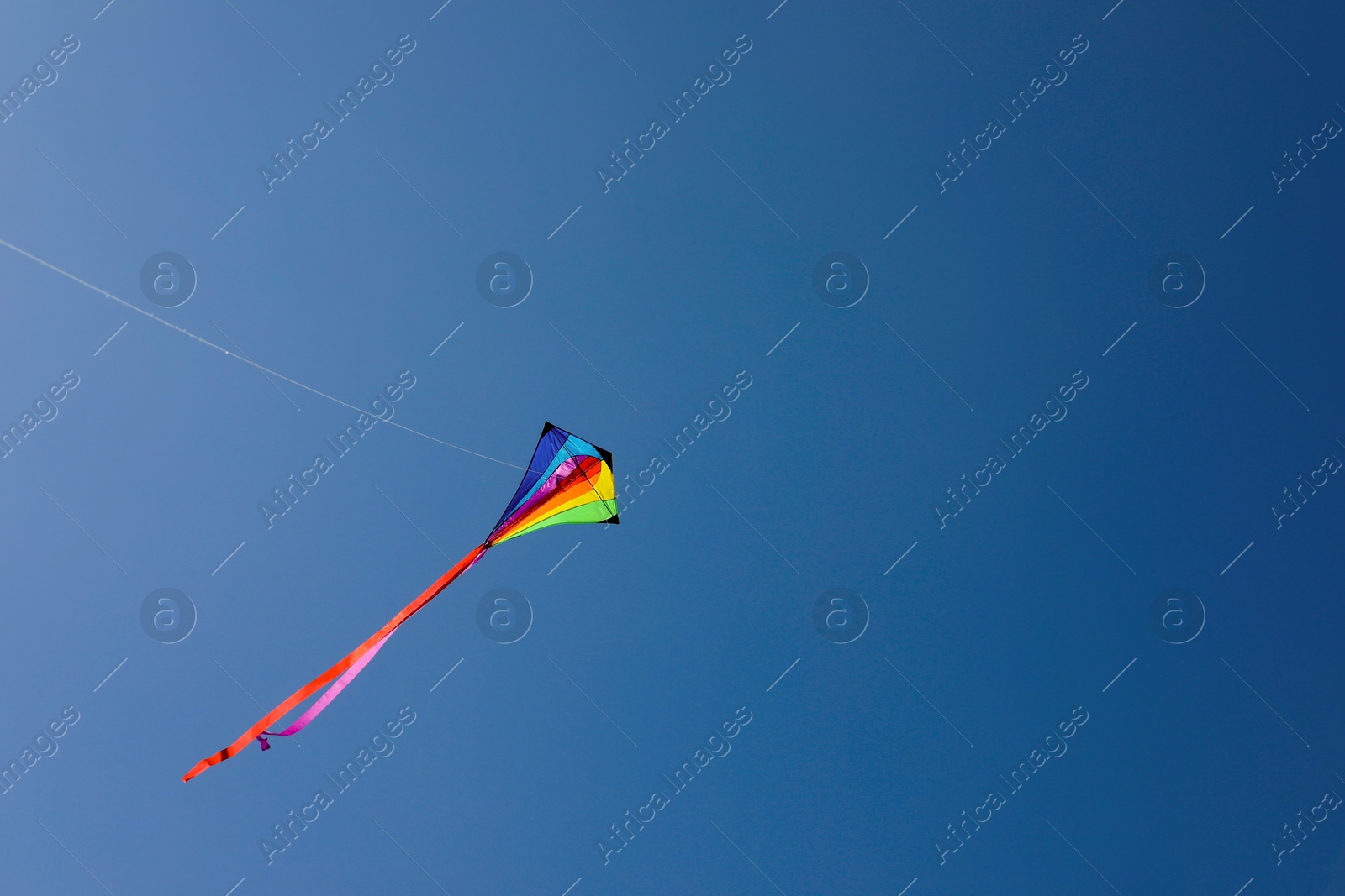 One colorful kite flying in blue sky. Space for text Photo of One colorful kite flying in blue sky. Space for text