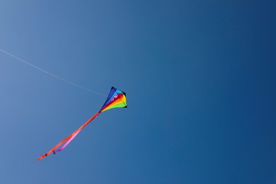 Photo of One colorful kite flying in blue sky. Space for text