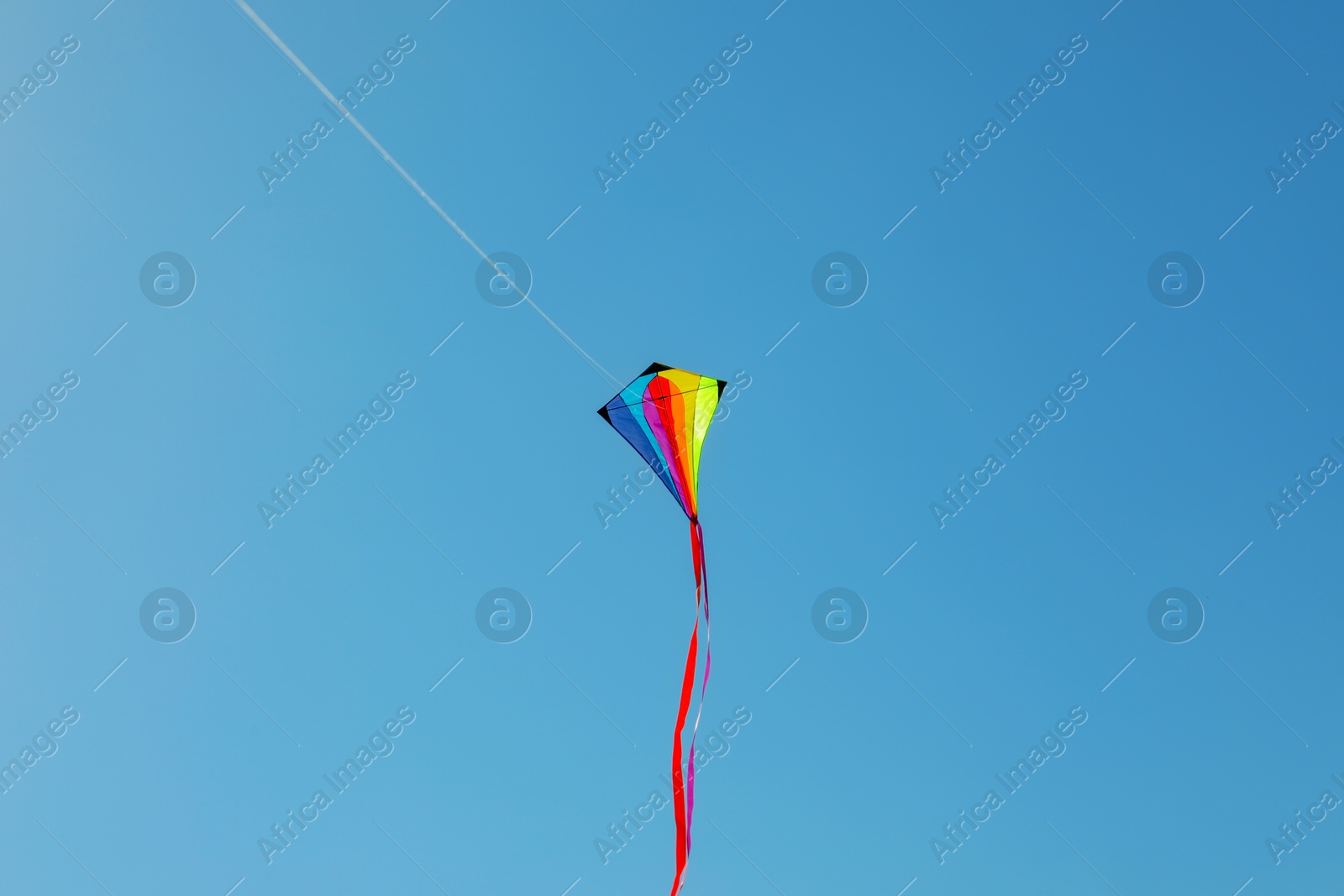 One colorful kite flying in blue sky Photo of One colorful kite flying in blue sky