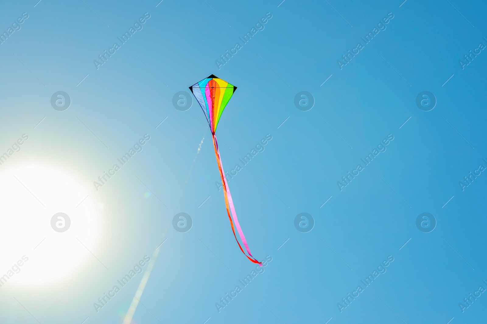 One colorful kite flying in blue sky on sunny day. Space for text Photo of One colorful kite flying in blue sky on sunny day. Space for text