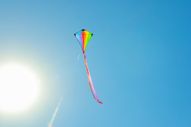 Photo of One colorful kite flying in blue sky on sunny day. Space for text