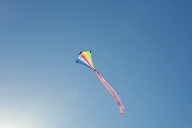 Photo of One colorful kite flying in blue sky on sunny day