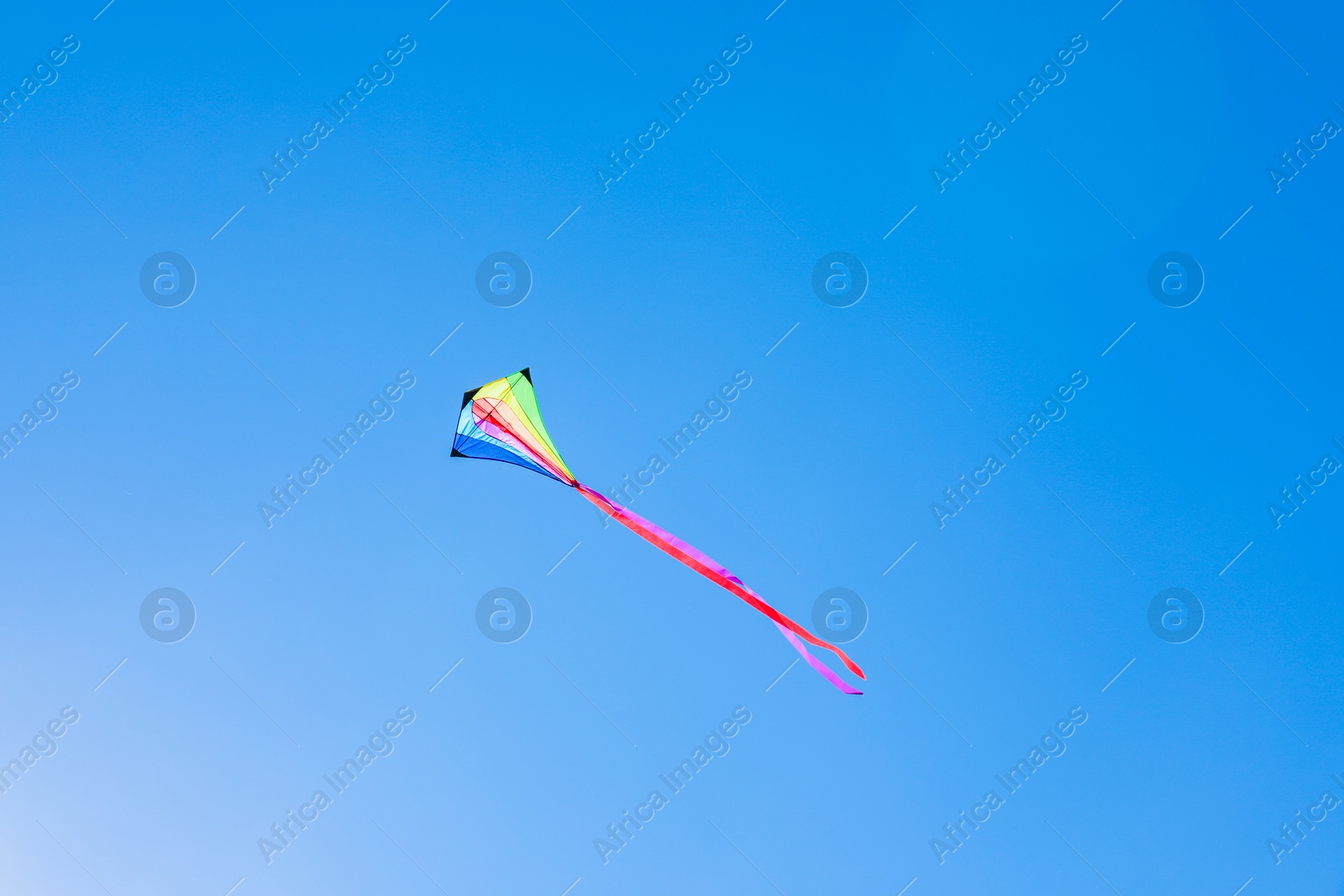 One colorful kite flying in blue sky on sunny day Photo of One colorful kite flying in blue sky on sunny day