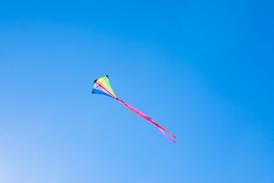 Photo of One colorful kite flying in blue sky on sunny day