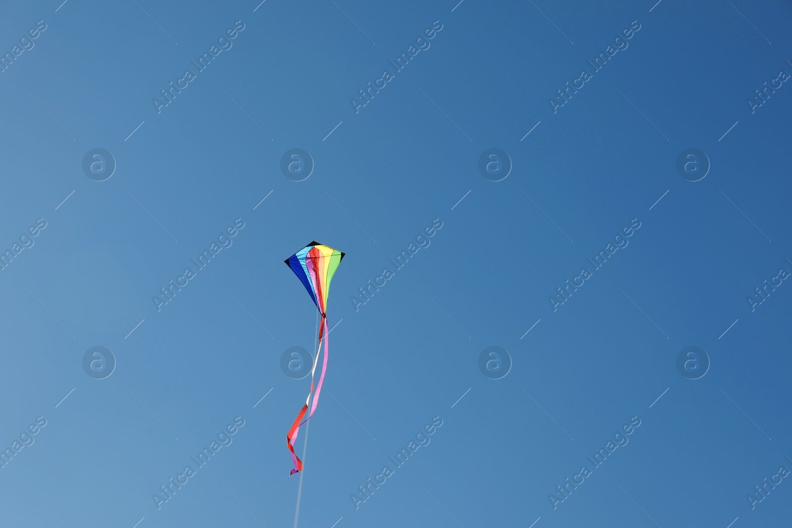 One colorful kite flying in blue sky. Space for text Photo of One colorful kite flying in blue sky. Space for text