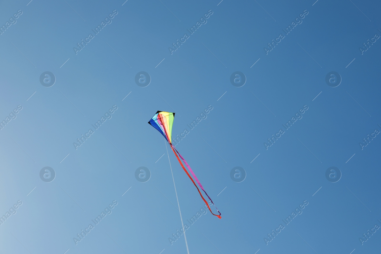 One colorful kite flying in blue sky Photo of One colorful kite flying in blue sky