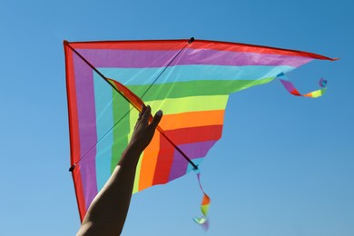 Photo of Woman with colorful kite against blue sky, closeup