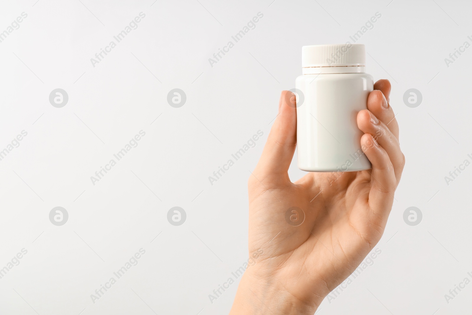 Photo of Woman holding medical bottle with pills on white background, closeup. Space for text