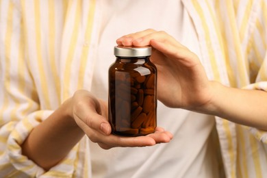 Photo of Woman holding medical bottle with pills, closeup