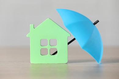 Photo of Property insurance. House figure and small umbrella on table